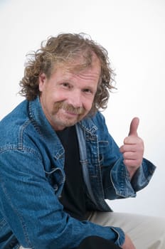Senior man in denim jacket sitting on a chair with thumbs up in elevated view