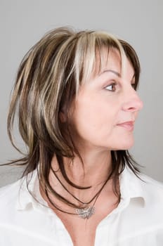 Head portrait of a mature blonde woman with dark streaks looking to the side with head and eyes