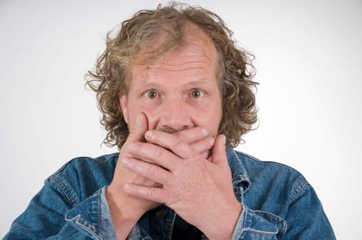 Head and shoulders portrait of an elderly man holding both hands over his mouth