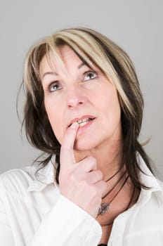 Head and shoulders shot of mature blonde woman with dark streaks in brooding/pensive pose