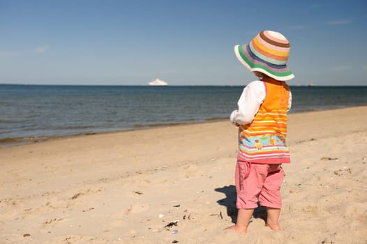 Little child by the sea with a view of a ship