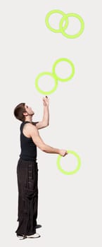 Young man juggling five rings.
