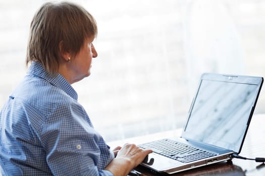 Elder woman working with laptop computer at home