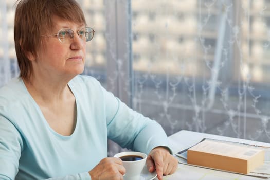 Elderly woman enjoying a cup of coffee at home