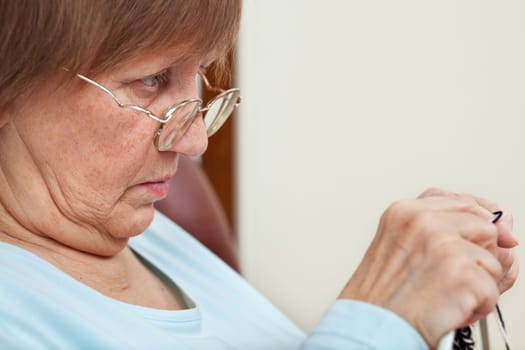 Elder woman doing knitting at home, focus on woman&#039 s eyes