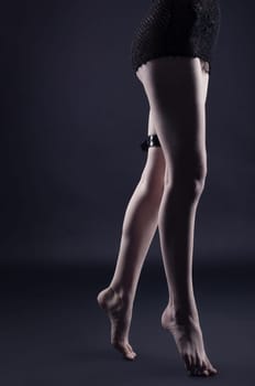 Woman legs in dark with leather belt - gothic style