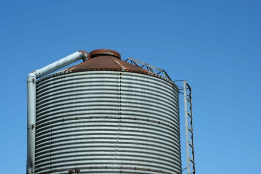A Metal feed silo against blue sky