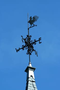 Rooster weather vane against blue sky