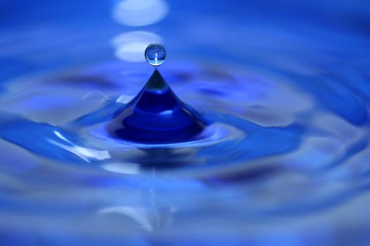 A blue water droplet splashing