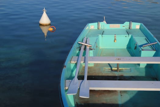 Small green boat with two paddles in it near a buoy in the waterlake of Annecy, France