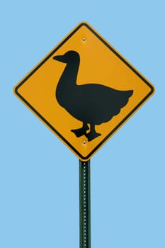 Duck crossing sign against a blue sky