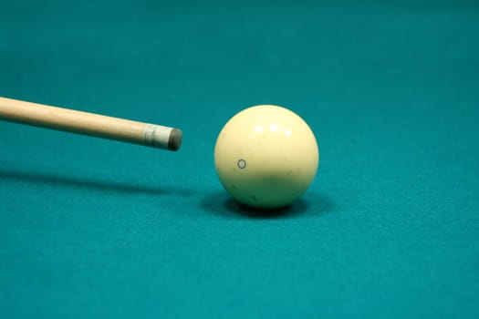 Pool stick and cue ball on a green table