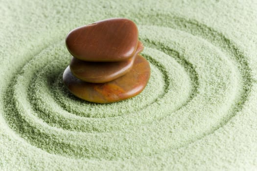 Brown stones in balance in a circle on green sand