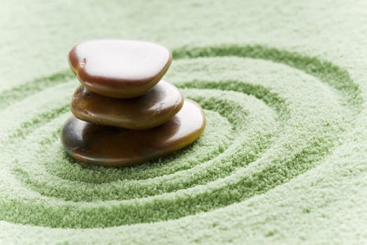 Brown stones in balance in a circle on green sand