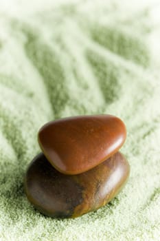 Brown stones in balance on green sand