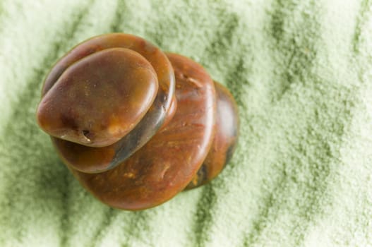 Brown stones in balance on green sand