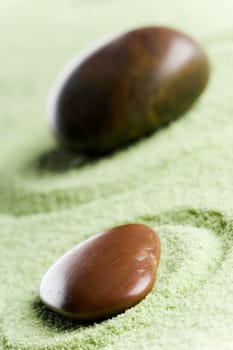 Brown stones in balance in a circle on green sand