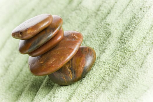 Brown stones in balance on green sand