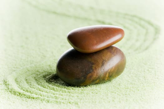 Brown stones in balance in a circle on green sand