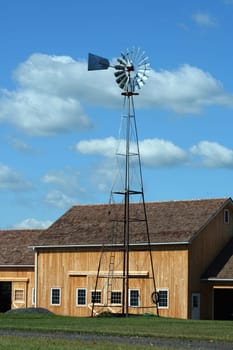 A Windmill with new barn against a cloudy blue sky