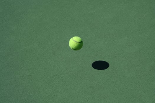 A empty green Tennis Court with bouncing ball