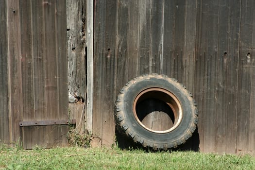 A Tire leaning on a old barn