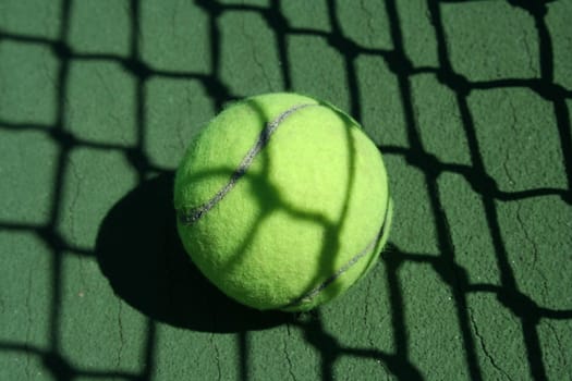 A Tennis ball near net with showdows
