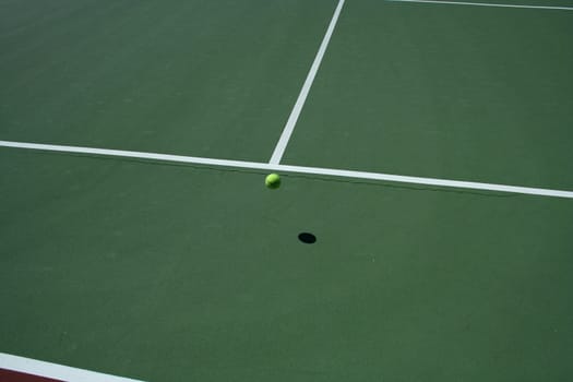 A empty green Tennis Court with bouncing ball