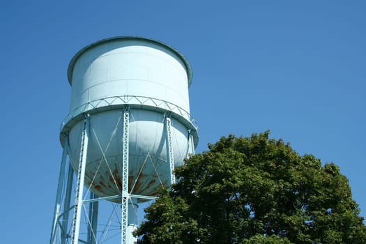Blue Water Tower against a blue sky and tree