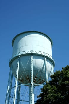 Blue Water Tower against a blue sky and tree