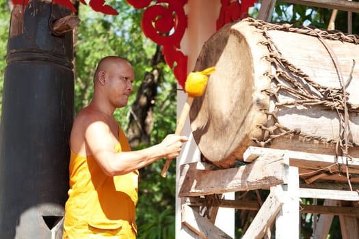 Buddhist monk beating the drum in the temple complex