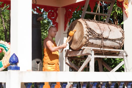 Buddhist monk beating the drum in the temple complex