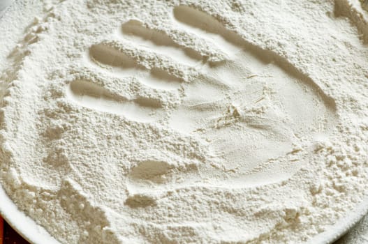 imprint of a woman&#039 s hand in a bowl with the flour