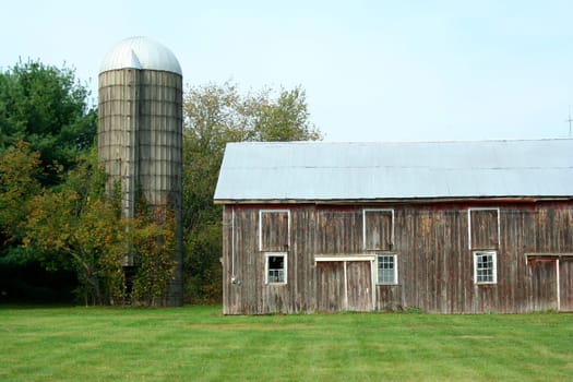 A Barn and silo with trees and grass