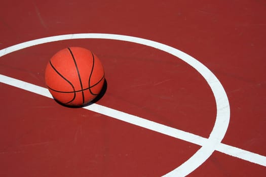 A Basketball at center court on a red court