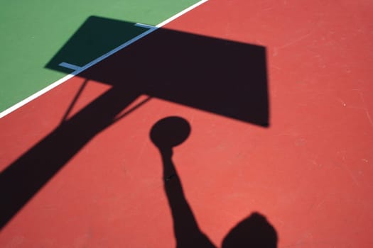 A Shadow Basketball player lay up on red and green court