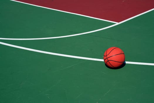 A Basketball at  three point line on red and green court