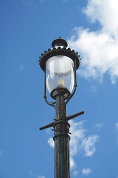 A black Lamp post against a blue sky