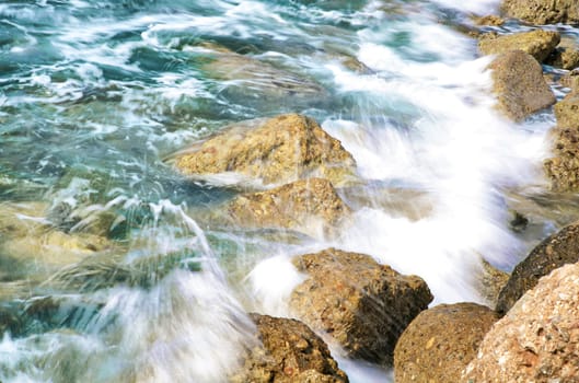 The rock on seashore with water and coming wave (long exposure)..