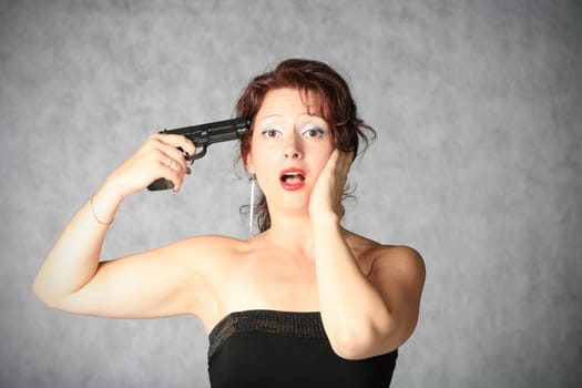 suicide - portrait of sexy redhead with pistol on the grey background