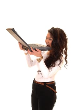 A pretty Asian woman is mad at her laptop and biting into them, on white background.