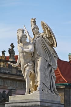 Two statues stand gaurd in front of neo classical buildings in Europe.