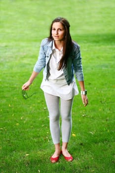 a young gorgeous woman is standing on the grass