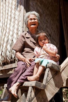 Asian grandmother with grandchild,portrait in front of Laotian house