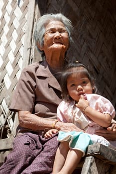 Asian grandmother with grandchild,portrait in front of Laotian house