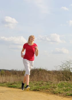 Young woman jogging on a dirt road
