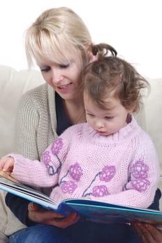Mother and daughter sitting in living room reading book