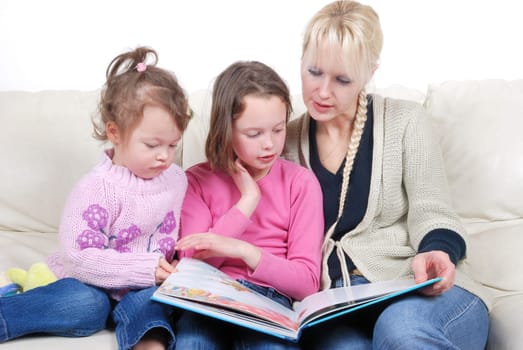 Mother and children sitting in living room reading book