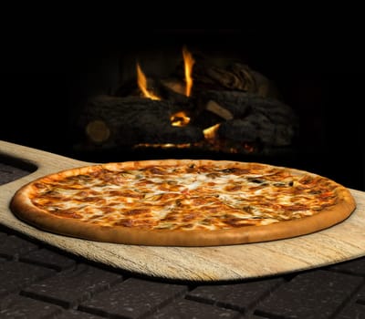 Pizza resting on a pizza peel near an open fire