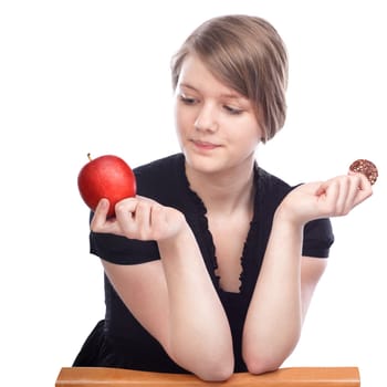 Young woman choosing between apple and chocolate cookies on white background